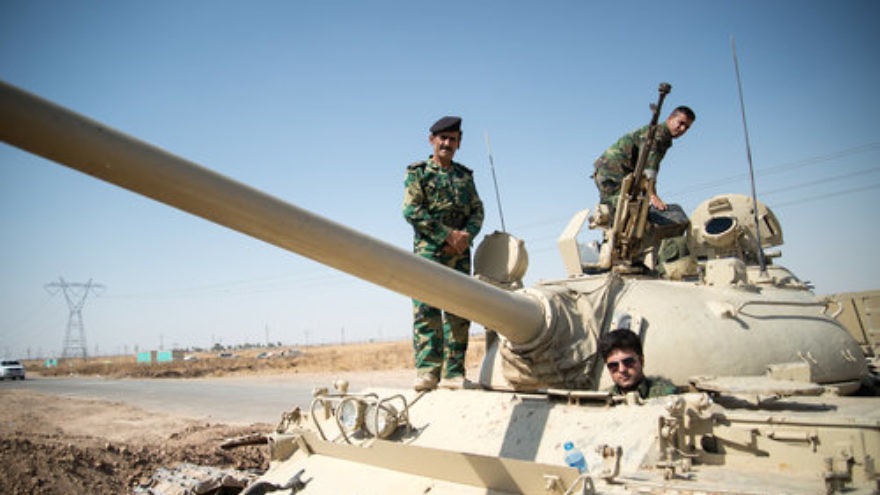 Members of the Kurdish Peshmerga forces on a tank outside Kirkuk, Iraq, in June 2014. Credit: Boris Niehaus via Wikimedia Commons.