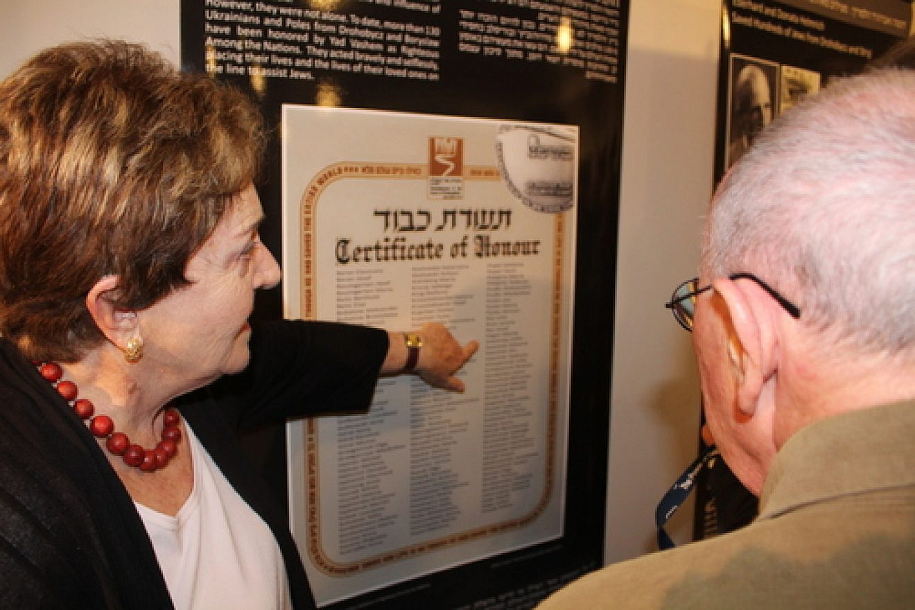 Standing in front of a poster at the Tel Aviv's Beit Hatfutsot museum with a list of individuals who had saved Jews in Drohobych-Boryslav during the Holocaust, Irena Wysoki points to the names “Jan Sawiński” and “Zofia Sawińska,” Polish farmers who hid Wysoki and her brother. Photo by Eitan Arom.