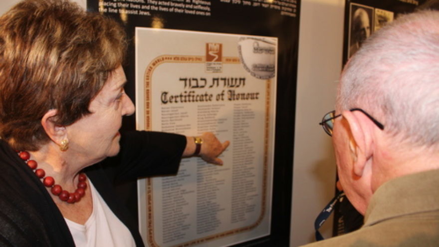 Standing in front of a poster at the Tel Aviv's Beit Hatfutsot museum with a list of individuals who had saved Jews in Drohobych-Boryslav during the Holocaust, Irena Wysoki points to the names “Jan Sawiński” and “Zofia Sawińska,” Polish farmers who hid Wysoki and her brother. Photo by Eitan Arom.