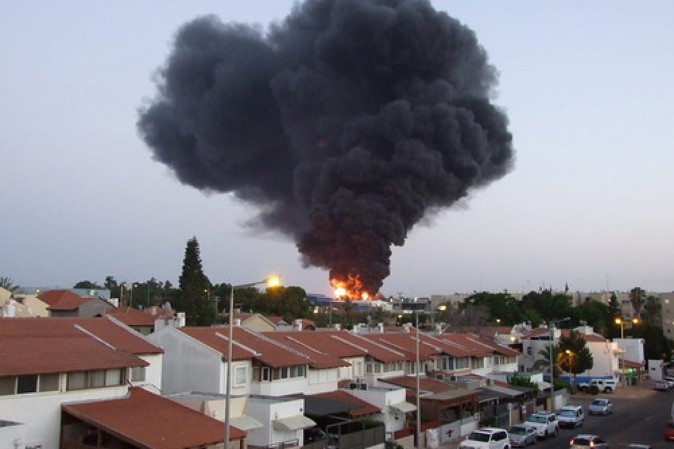 A factory in the southern Israeli city of Sderot bursts into flames after being hit by a rocket from Gaza during the 2014 Hamas-Israel conflict. Credit: Natan Flayer via Wikimedia Commons.