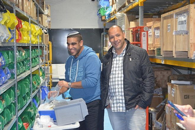 Chen Orpaz (left) with IDF Lt. Col. (Ret.) Ariel Almog, founder of "Special in Uniform," in the warehouse of the Rehovot-based technology company IDEA. Orpaz, who has an intellectual disability, now works at IDEA after picking up the skills he needed from working in the warehouse on an air force base as part of the Special in Uniform project. Credit: Courtesy Jewish National Fund.