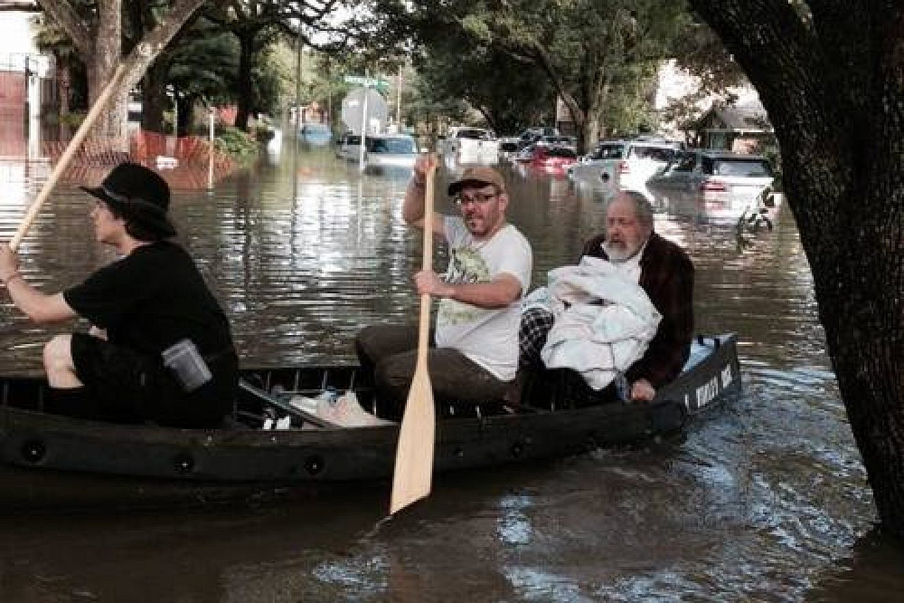 The iconic photo of Morgan Davies (far left) and Donniel Ogorek (center) rescuing Rabbi Joseph Radinsky (right) from the flood in Houston. Credit: Robert Levy via Facebook.