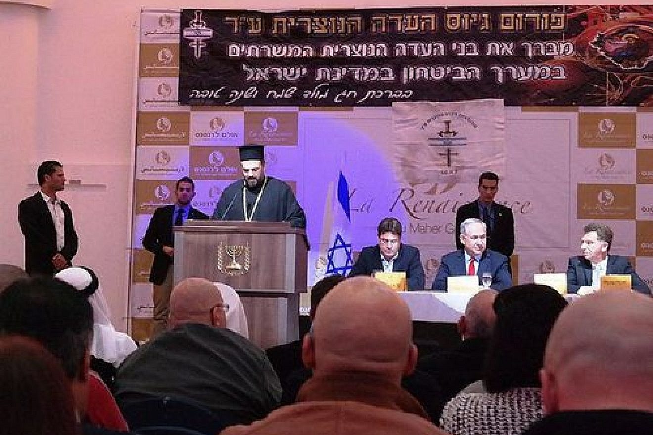 Click photo to download. Caption: Father Gabriel Naddaf addresses Christian IDF soldiers in December 2014, with Israeli Prime Minister Benjamin Netanyahu (sitting at table, in center) in attendance. Credit: Maor X via Wikimedia Commons.