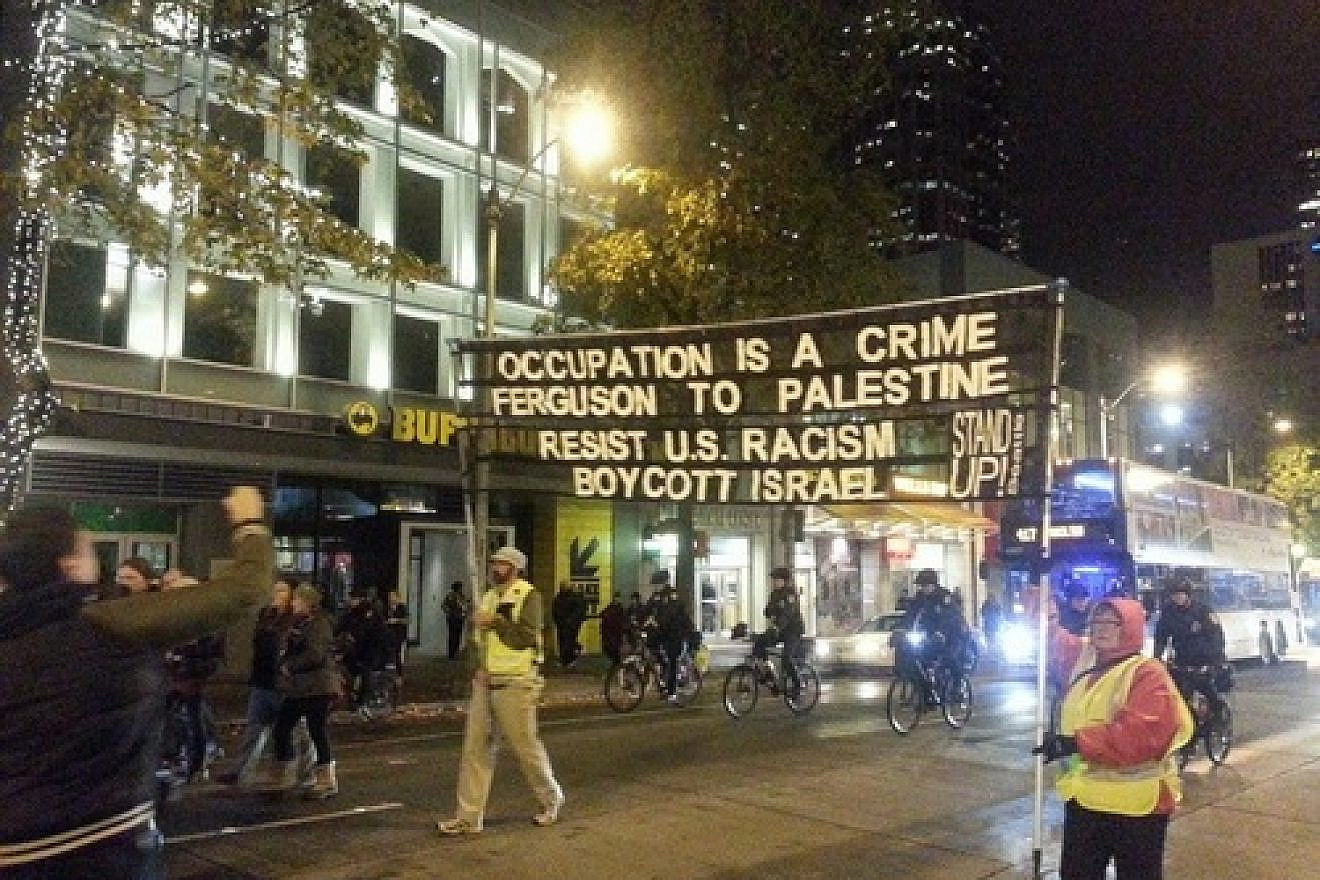 In a protest against the Ferguson verdict on Nov. 24 in Seattle, a sign uses the situation as a platform to promote a boycott of Israel. Credit: The Mike Report.