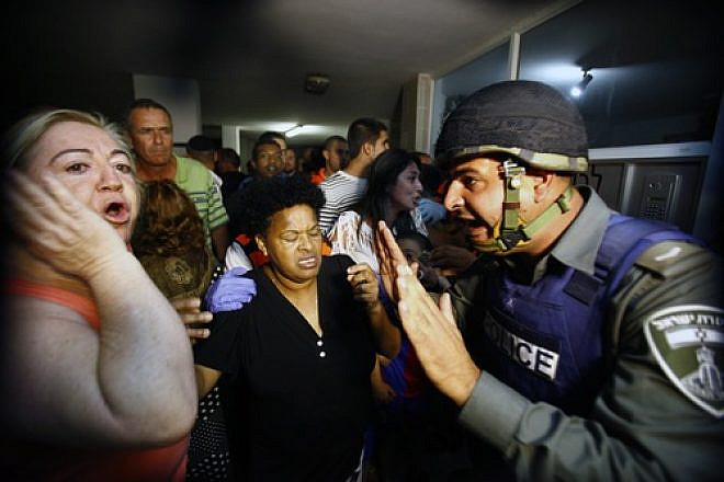 An Israeli border policeman tries to comfort residents in an apartment building after a Grad missile fired by Palestinian terrorists inside the Gaza strip exploded outside their building in Ashdod, Israel, on Oct. 29, 2011. Credit: EPA/EDI ISRAEL.