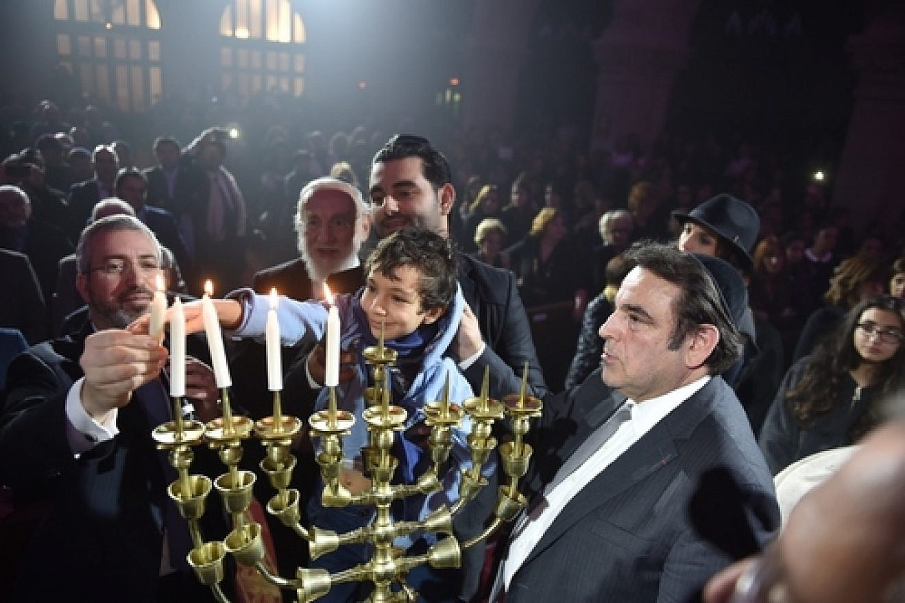 Relatives of the Hyper Cacher terrorist attack victims (Philippe Braham, Yohan Cohen, Yoav Hattab, and François-Michel Saada) light Hanukkah candles at this week's “Let There Be Light: A Concert of Jewish Unity” at the Grande Synagogue de la Victoire (the Great Synagogue of Paris). Credit: Israel Bardugo.