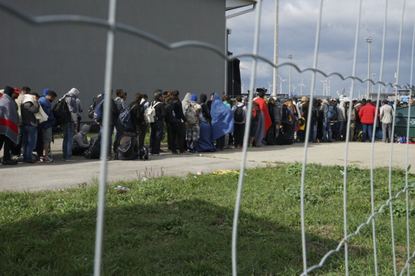 Syrian refugees wait in line to cross the border of Hungary and Austria on their way to Germany in September 2015. Credit: Mstyslav Chernov via Wikimedia Commons.
