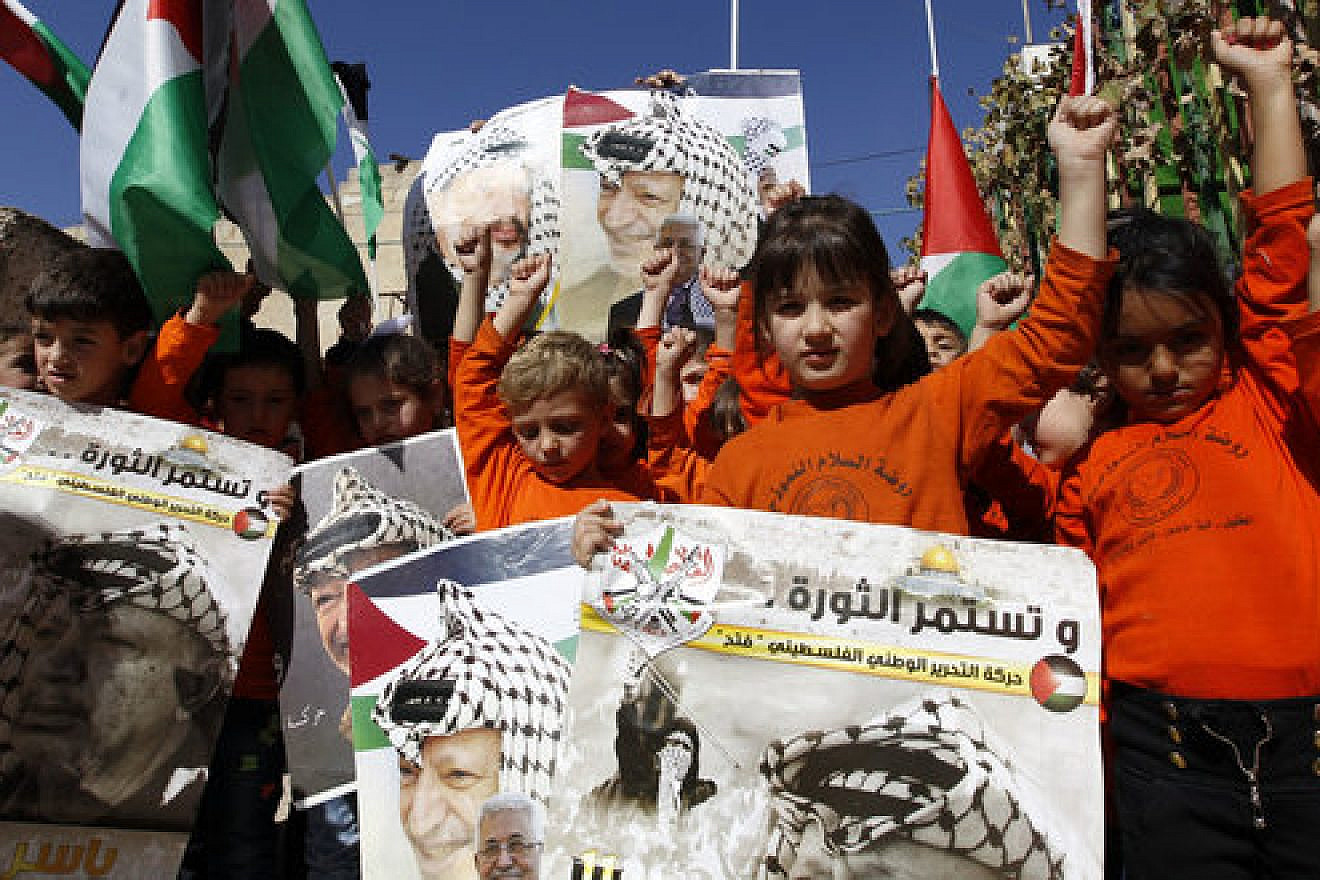 Palestinian children hold posters with the picture of former Palestinian head Yasser Arafat and current Palestinian Authority leader Mahmoud Abbas during a rally in Hebron marking the 12th anniversary of Arafat’s death Nov. 10, 2016. Credit: Wisam Hashlamoun/Flash90.
