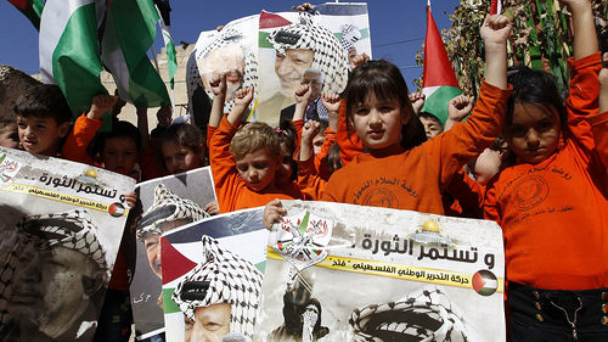Palestinian children hold posters with the picture of former Palestinian head Yasser Arafat and current Palestinian Authority leader Mahmoud Abbas during a rally in Hebron marking the 12th anniversary of Arafat’s death Nov. 10, 2016. Credit: Wisam Hashlamoun/Flash90.