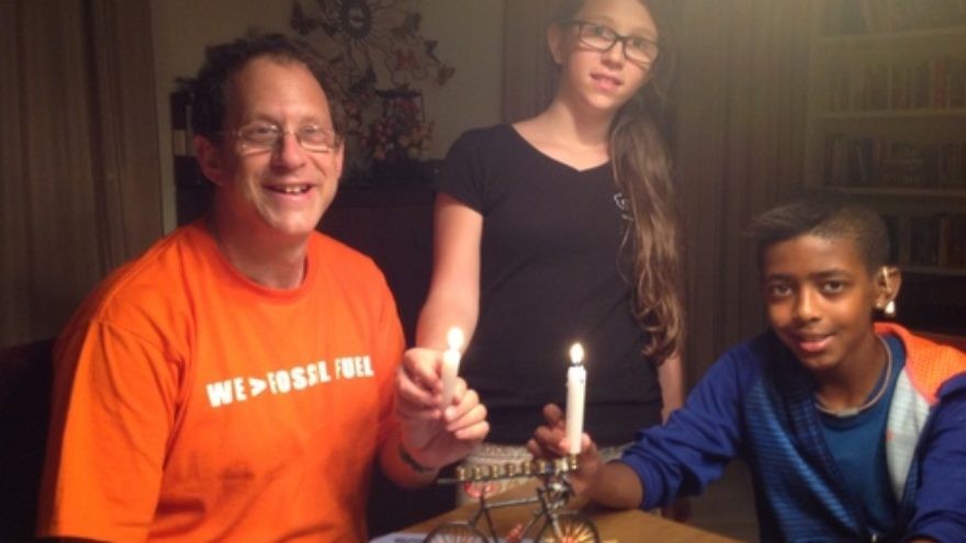 Solar-power pioneer Yosef Abramowitz (left) pictured with two of his five children, Ashira and Zamir, as the family uses its bicycle-shaped Hanukkah menorah. Credit: Courtesy Yosef Abramowitz.