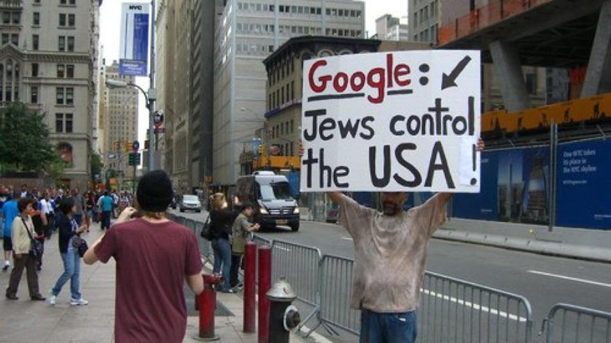 A man holds a sign promoting an anti-Semitic conspiracy theory across the street from the former World Trade Center site on Sept. 11, 2011, the 10th anniversary of the 9/11 attacks. Credit: Luigi Novi via Wikimedia Commons.