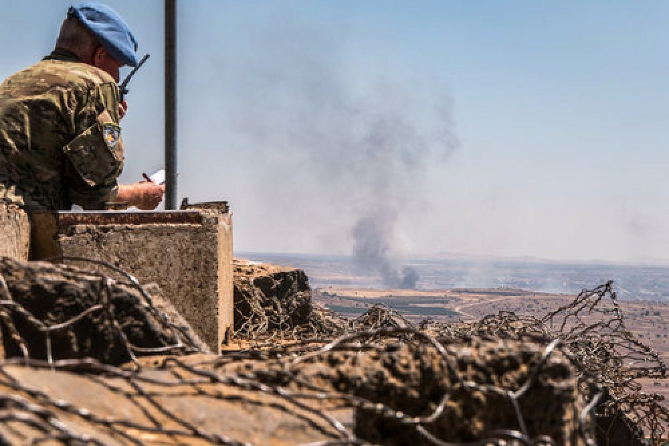 A U.N. observer is stationed at a lookout point as smoke rises in a Syrian village near the Israel border in the Golan Heights during fighting in the Syrian civil war, June 25, 2017. Credit: Basel Awidat/Flash90.