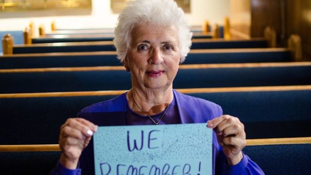 A woman holds a “We Remember” sign as part of the the World Jewish Congress's social media campaign. Credit: Facebook.