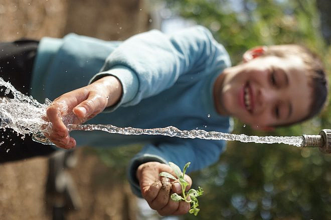 A child plays with water, a precious resource in Israel. Credit: Jewish National Fund.