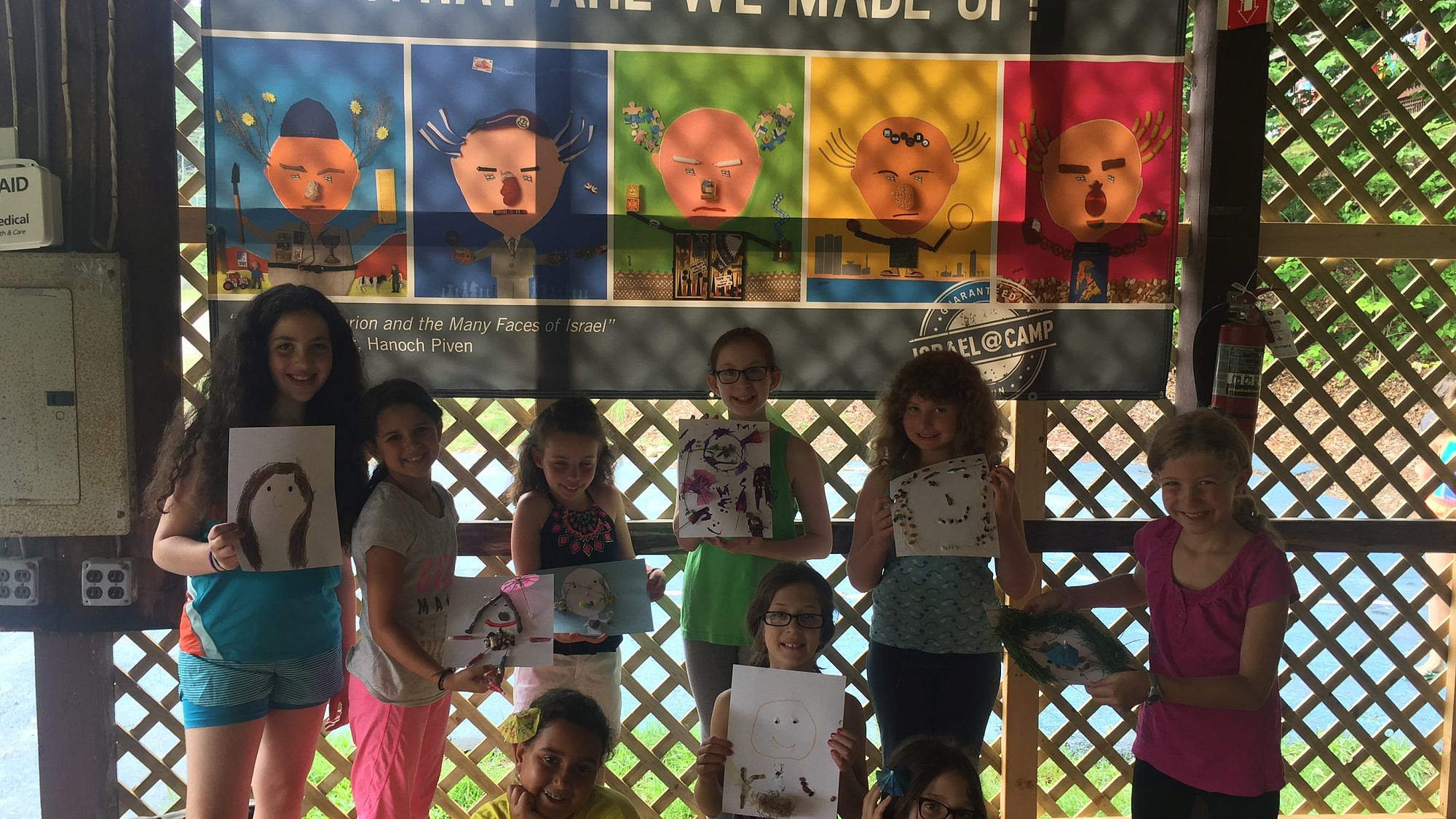 Campers show off their Hanoch Piven-inspired portraits in front of their Israel @ Camp banner. Credit: iCenter for Israel Education.