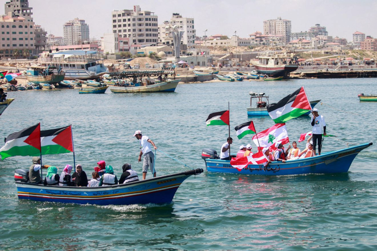 Palestinians hold flags as they ride a boat during a rally marking the fifth anniversary of the “Mavi Marmara” Gaza flotilla at the seaport of Gaza City on May 31, 2015. Photo by Aaed Tayeh/Flash90.