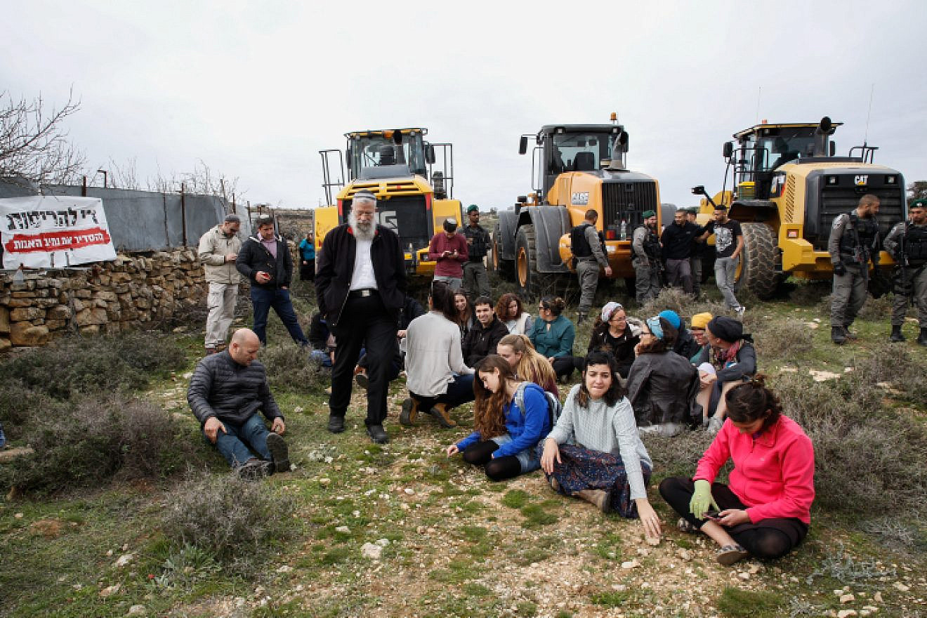Civil administration representatives and Israelii Border Police arrive with tractors to begin preparations for evacuation and demolition of the illegal Jewish neighborhood of Netiv Ha’avot, as Jewish settlers block their way, Feb. 6, 2018. Photo by Gershon Elinson/Flash90.