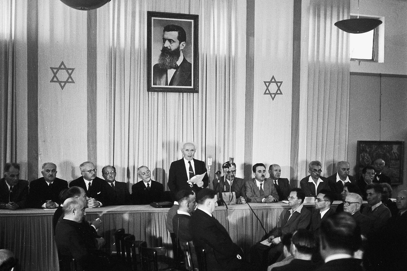 Israeli founding father and first prime minister David Ben-Gurion declares independence beneath a large portrait of Theodor Herzl, founder of modern Zionism. Credit: Wikimedia Commons.