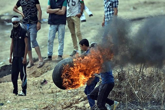 Palestinians burn tires to throw over the Gaza border into Israel on May 4, 2018, as part of weekly riots led by Hamas since March 30. Credit: Wikimedia Commons.