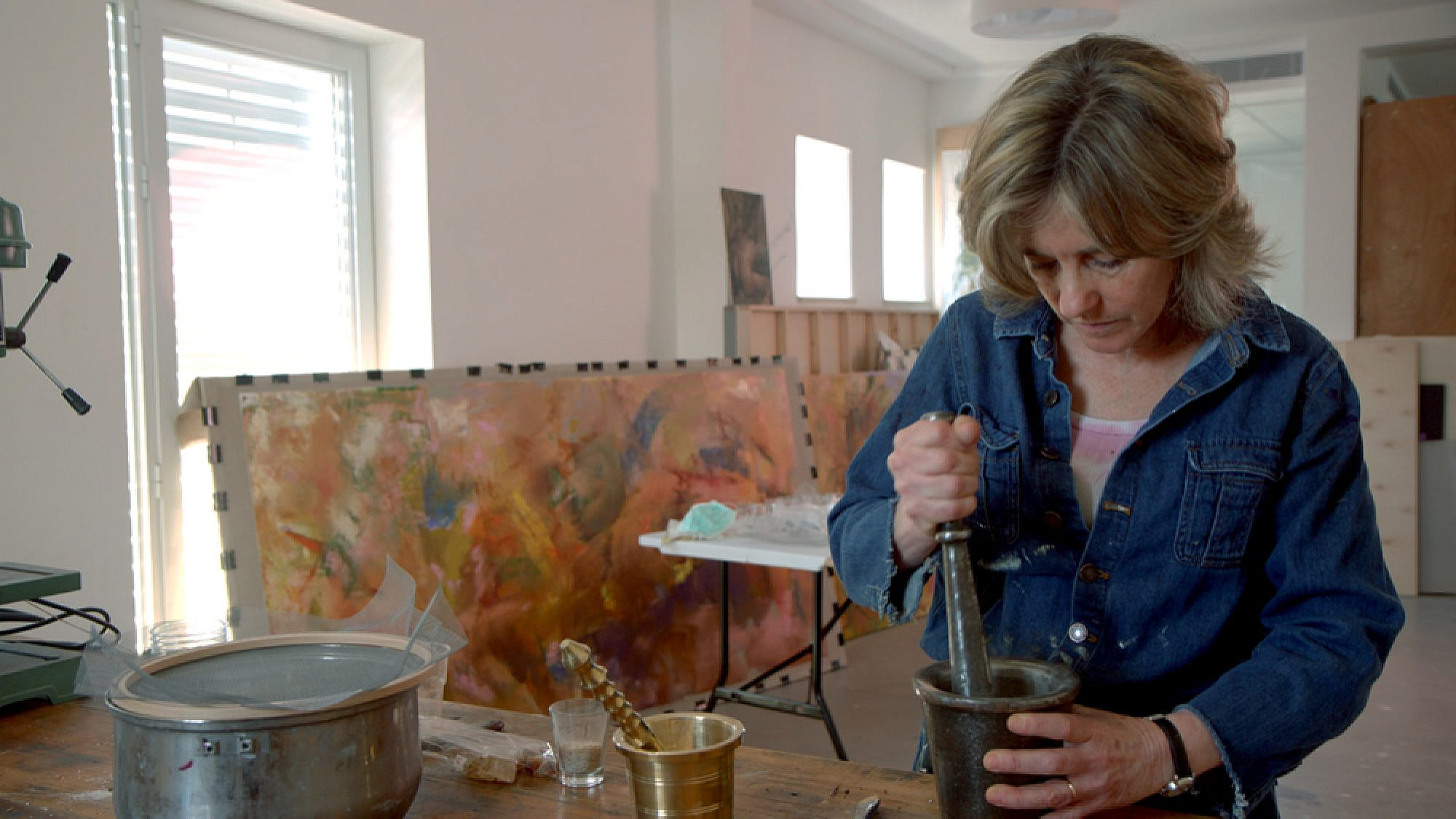 Beverly Barkat grinds material into fragments with a pestle and mortar for her artwork “After the Tribes,” to be exhibited in Rome. Credit: Photo by Tor Ben Mayor.