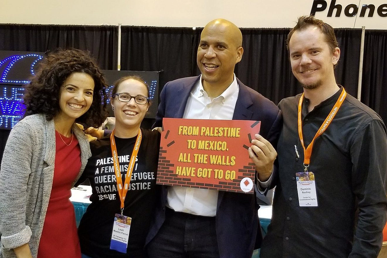 U.S. Sen. Cory Booker (D-N.J.) holds a sign reading: “From Palestine to Mexico, all the walls have got to go.” Credit: Twitter via U.S. Campaign for Palestinian Rights.