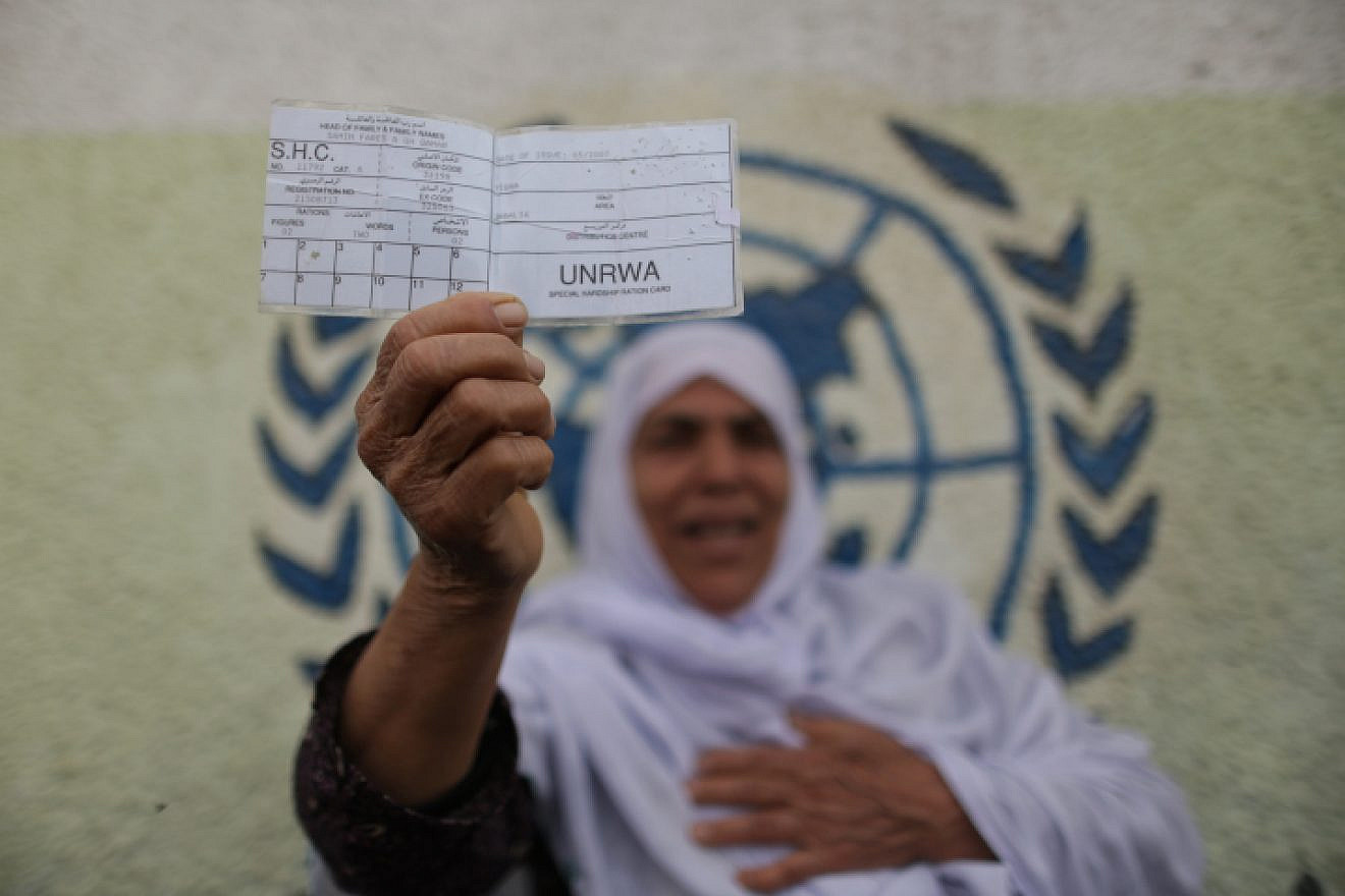 A Palestinian woman stands in front of UNRWA headquarters in Gaza City holding a refugee ration card during a protest demanding that the U.N. agency resume aid, April 8, 2013. Photo by Wissam Nassar/Flash90.