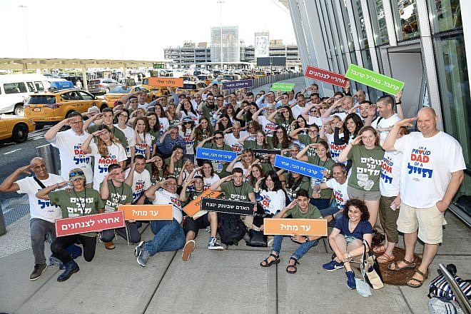 A group of soon-to-be volunteers in the Israel Defense Forces gather outside of John F. Kennedy Airport in New York and salute their future. Credit: Shahar Azram.