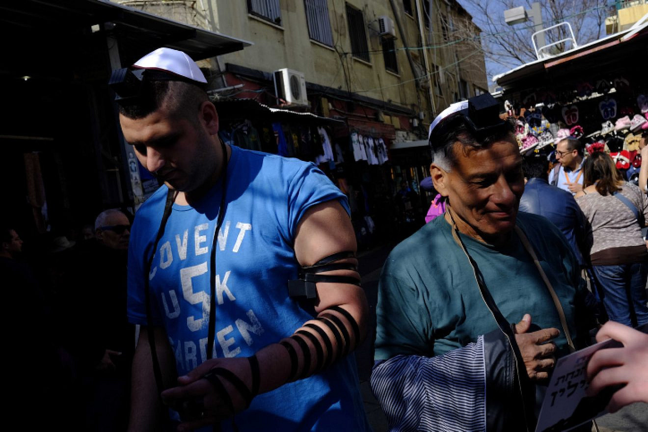 Israeli Jewish men put on tefillin at the entrance to Carmel Market in downtown Tel Aviv on Feb. 10, 2017. Photo by Tomer Neuberg/Flash90.
