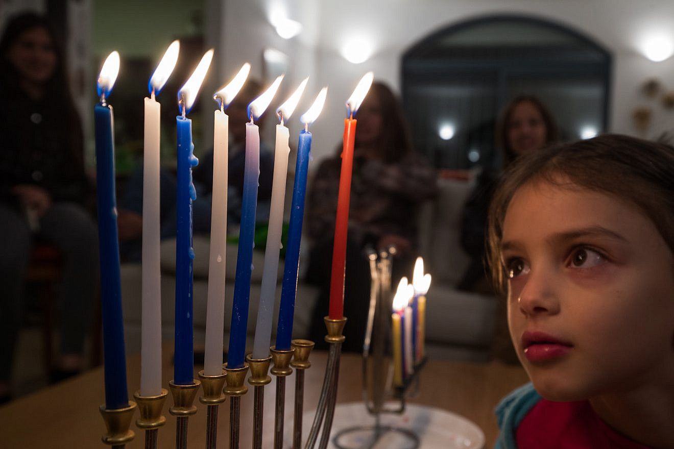 A child observes the candles on a fully lit Hanukkah menorah, Dec. 12, 2015. Photo by Nati Shohat/Flash90.
