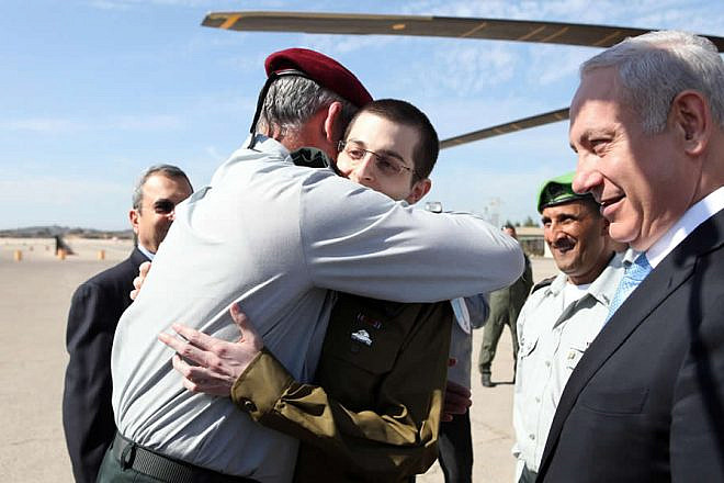 Israel Defense Forces Chief of Staff Lt. Gen. Benny Gantz embraces IDF soldier Gilad Shalit upon his return from captivity, alongside Israeli Prime Minister Benjamin Netanyahu, on Oct. 18, 2011. Credit: IDF Photo via Wikimedia Commons.