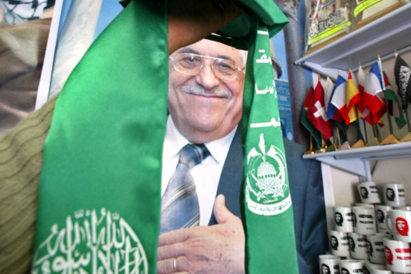 Gaza City, Gaza Strip on Feb. 7, 2006: Palestinian Abu Dayya holds up the Hamas flag in front of a poster of Mahmoud Abbas in his shop in Gaza City. Photo by Ahmad Khateib/Flash90.