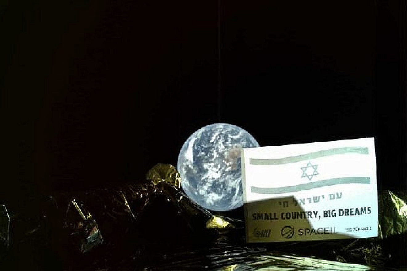 A photo by the Beresheet spacecraft, in which an Israeli flag can be seen on a plaque with the inscription, “Am Israel Chai,” or “the Jewish people lives,” and in English, “Small country, big dreams,” taken 23,360 miles from Earth. Credit: SpaceIL/IAI.