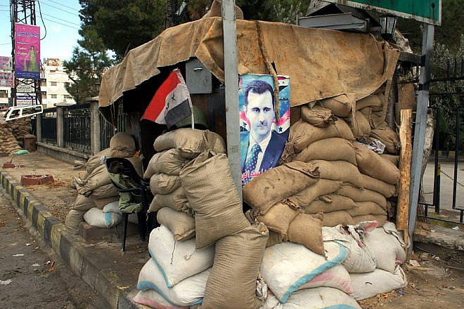 A poster of Syrian President Bashar Assad attached to a checkpoint on the outskirts of Damascus, Jan. 14, 2012. Credit: Elizabeth Arrott via Wikimedia Commons.