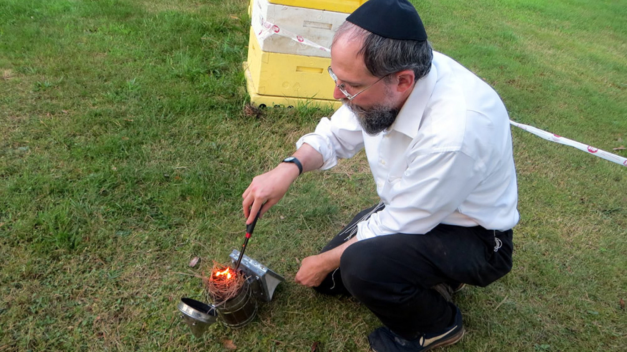 Rabbi Avraham Laber, co-director of Chabad-Lubavitch of Southern Rensselaer County in New York, uses smoke to calm honey bees before opening a hive. Photo by Carin M. Smilk.