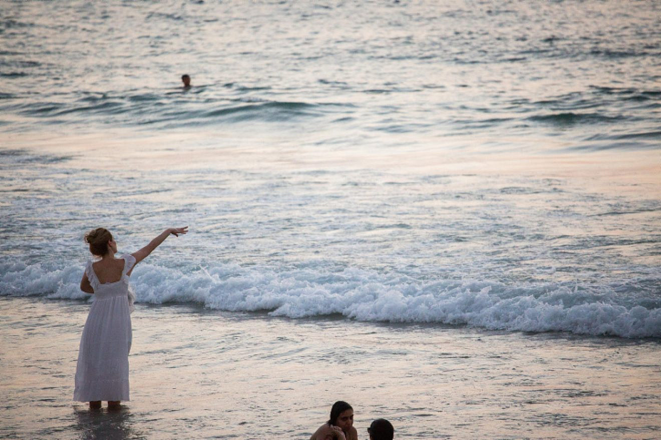 A woman performs "tashlich," a Jewish ritual performed before the eve of Rosh Hashanah, at the beach in Tel Aviv, on Sept. 10, 2018. Photo by Yonatan Sindel/Flash90.