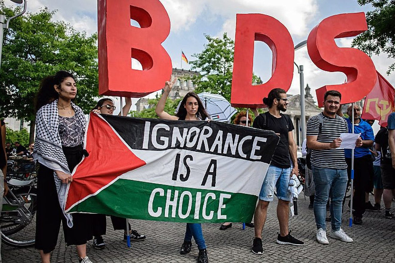 Protesters in Berlin hold a Palestinian flag and the initials of the anti-Israel BDS movement while then-Israeli Prime Minister Benjamin Netanyahu was visiting Germany in August 2019. Credit: Israel Hayom.