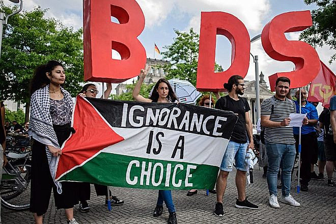 Protesters in Berlin hold a Palestinian flag and the initials of the anti-Israel BDS movement while then-Israeli Prime Minister Benjamin Netanyahu was visiting Germany in August 2019. Credit: Israel Hayom.