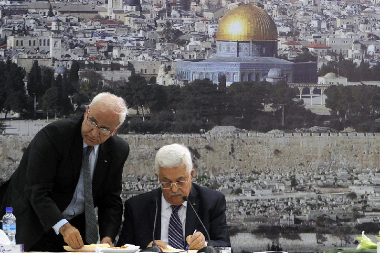 P.A. leader Mahmoud Abbas (right) and Palestinian chief negotiator Saeb Erekat sign an application to U.N. agencies in the West Bank city of Ramallah on April 1, 2014. Photo by Issam Rimawi/Flash90.