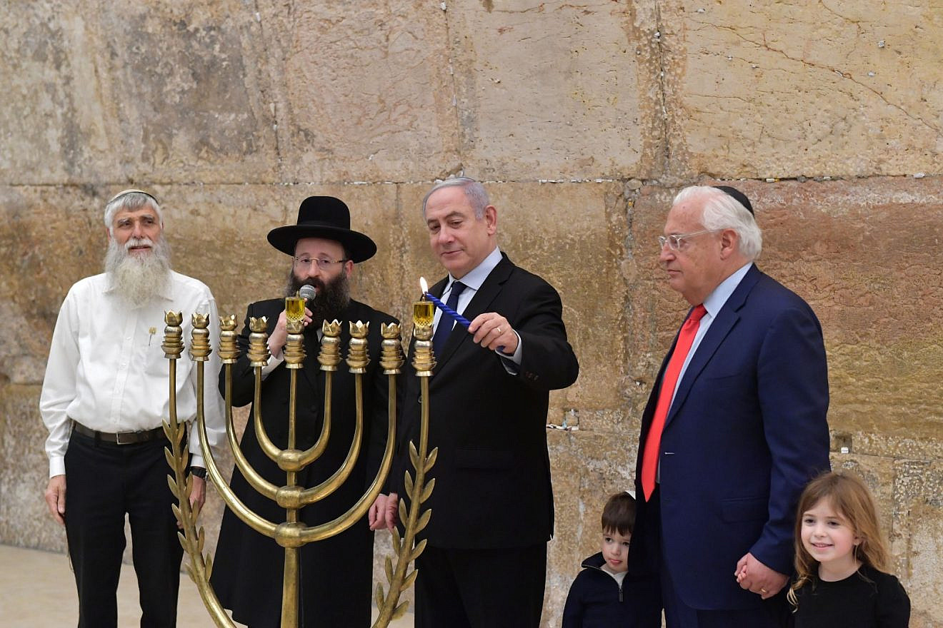 Then-Israeli Prime Minister Benjamin Netanyahu and U.S. Ambassador David Friedman (right) light the first Hanukkah candle at the Western Wall in Jerusalem. To Netanyahu's left is Rabbi Shmuel Rabinovitch, rabbi of the Western Wall, and next to him is Mordechai “Suli” Elias, director of the Western Wall Heritage Foundation, Dec. 22, 2019. Photo by Koby Gideon/GPO.