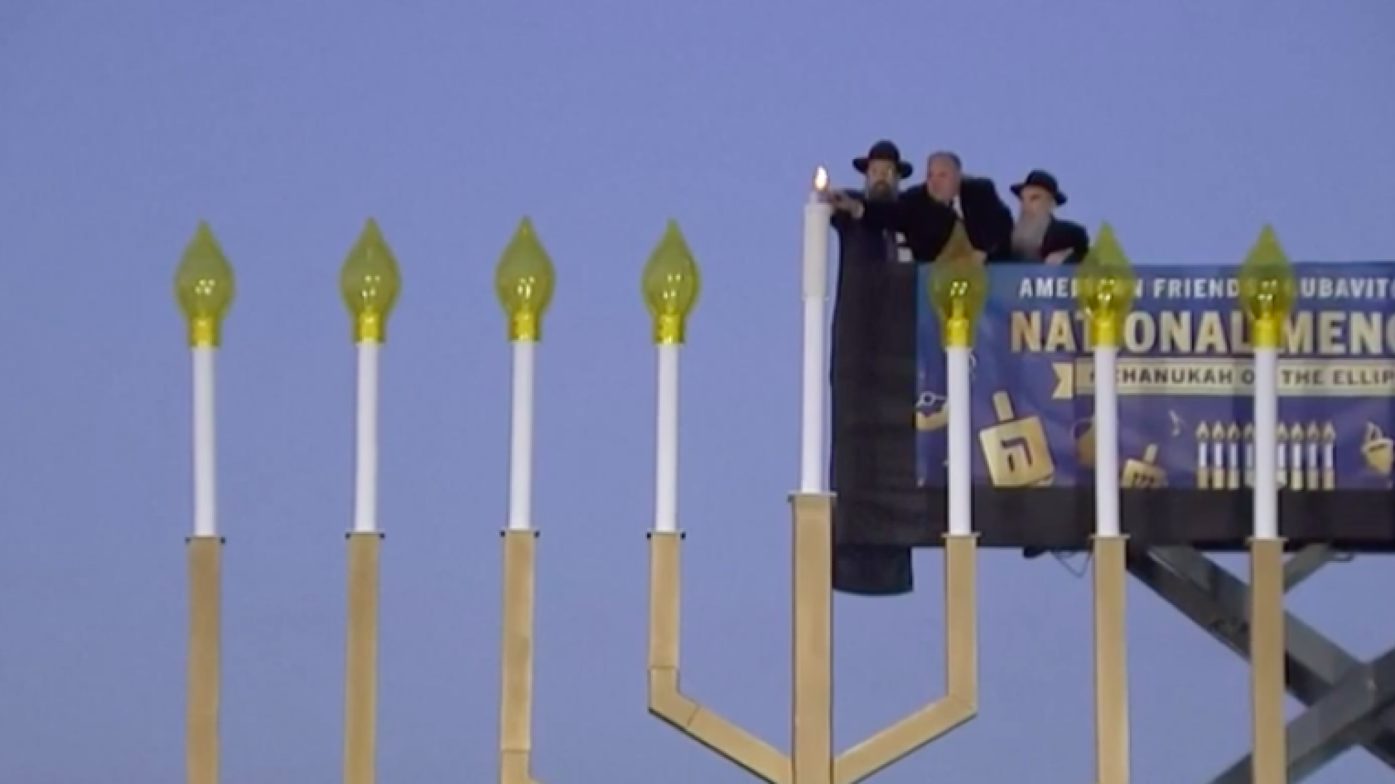 U.S. Interior Secretary David Bernhardt (center) helps light the shamash ("helper candle") of the National Menorah on the Ellipse near the White House in Washington, D.C., on Dec. 22, 2019, assisted by Rabbi Levi Shemtov (left), executive vice president of American Friends of Lubavitch (Chabad), and his father, Abraham Shemtov. Source: Screenshot.
