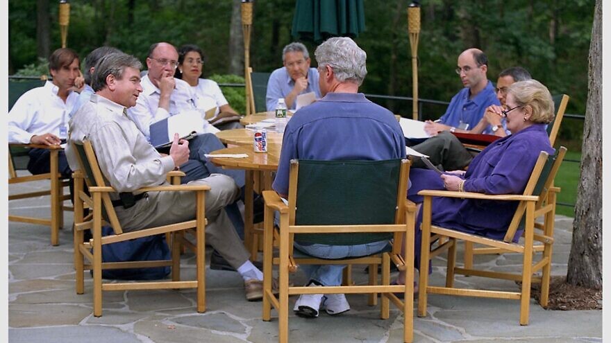 U.S. President Bill Clinton with Secretary of State Madeleine Albright (right), National Security Advisor Sandy Berger (left) and other staff, including former Mideast negotiator Aaron David Miller (back left) and Robert Malley (back right) at Camp David during Israeli-Palestinian negotiations in 2000. Credit: White House Photo via Israel GPO.
