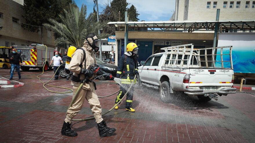 Palestinian municipal workers disinfect the parking lot of a hospital, in the West Bank city of Ramallah, March 12, 2020. Photo by Flash90.