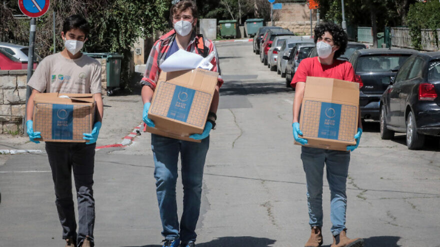 Young Israeli volunteers give away hot meals to elderly people unable to leave their homes because of the coronavirus outbreak, in Jerusalem on March 29, 2020. Photo by Yossi Zamir/Flash90.