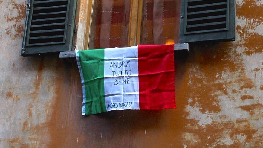 An Italian flag hangs outside a window in Bologna on March 19, 2020, bearing the slogan “Andrà tutto bene” (“Everything is going to be fine”) during the COVID-19 pandemic in 2020. Photo: Pietro Luca Cassarino via Wikimedia Commons.