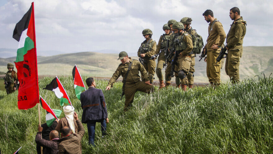 Israeli troops look on as Palestinian demonstrators protest against U.S. President Donald Trump's Middle East peace plan, near the town of Beqa'ot in the Jordan Valley, Feb. 29, 2020. Photo by Nasser Ishtayeh/Flash90.