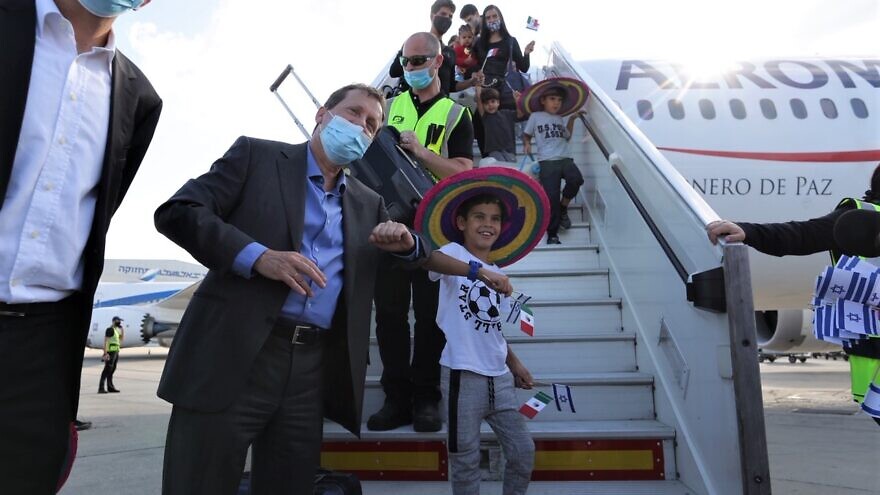 Jewish Agency chair Isaac Herzog gives an elbow-bump welcome to kids descending a charter flight as part of “Operation Home,” Aug. 11, 2020. Photo by Dudi Salem/The Jewish Agency for Israel.