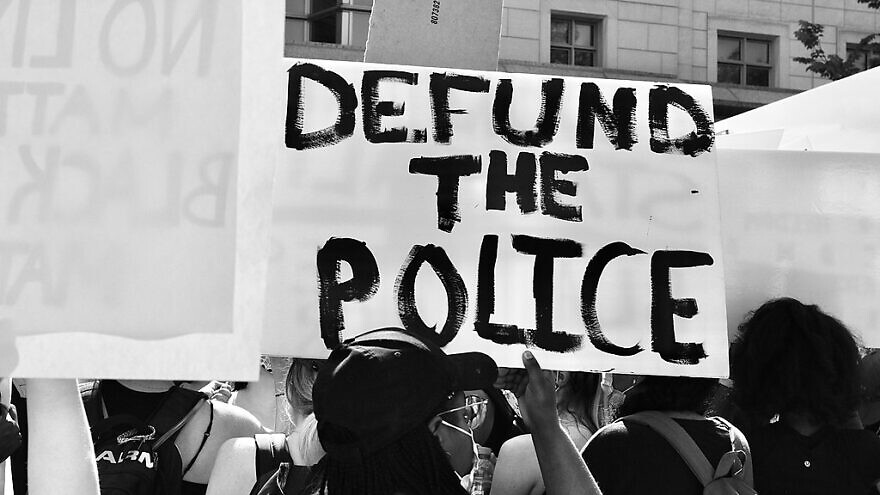 A demonstrator at a George Floyd protest holds up a “Defund the Police” sign on June 5, 2020. Credit: Taymaz Valley via Wikimedia Commons.
