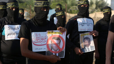 Members of the Al-Quds Brigades, the military wing of the Palestinian Islamic Jihad, hold pictures of French President Emmanuel Macron during a protest march in the southern Gaza Strip against the reprinting of a cartoon of the Prophet Muhammad in France, on Oct. 26, 2020. Photo by Abed Rahim Khatib/Flash90.
