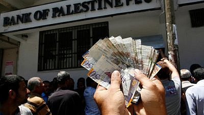 An employee of the Palestinian Authority displaying money he withdrew from a bank in Gaza City on June 11, 2014. Photo by Abed Rahim Khatib/Flash90.