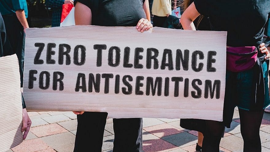 A woman holds a sign opposing antisemitism at a rally. Photo by AndriiKoval/Shutterstock.